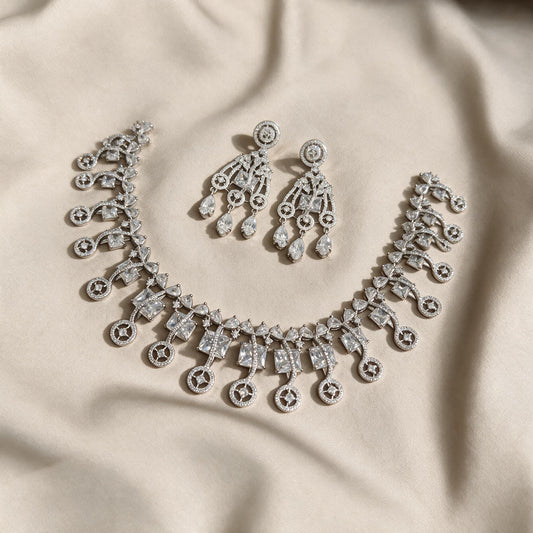 Necklace and matching earrings arranged on ivory fabric.