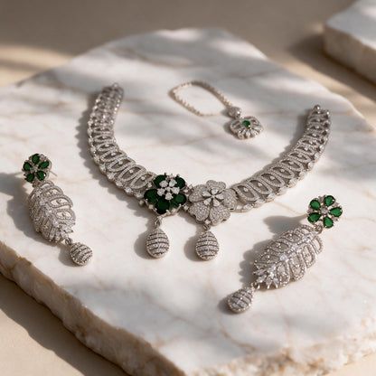 Angled marble view of the necklace, pair of earrings and separate floral chain ornament.