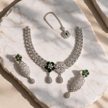 Meher silver-tone necklace, matching green floral drop earrings and chain-mounted floral ornament arranged on marble.