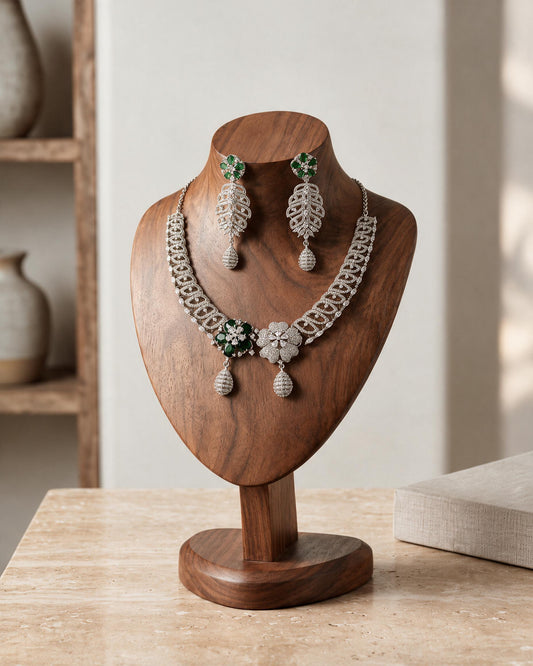 Front view of the Meher necklace and earrings on a wooden display, showing green and clear floral centres.