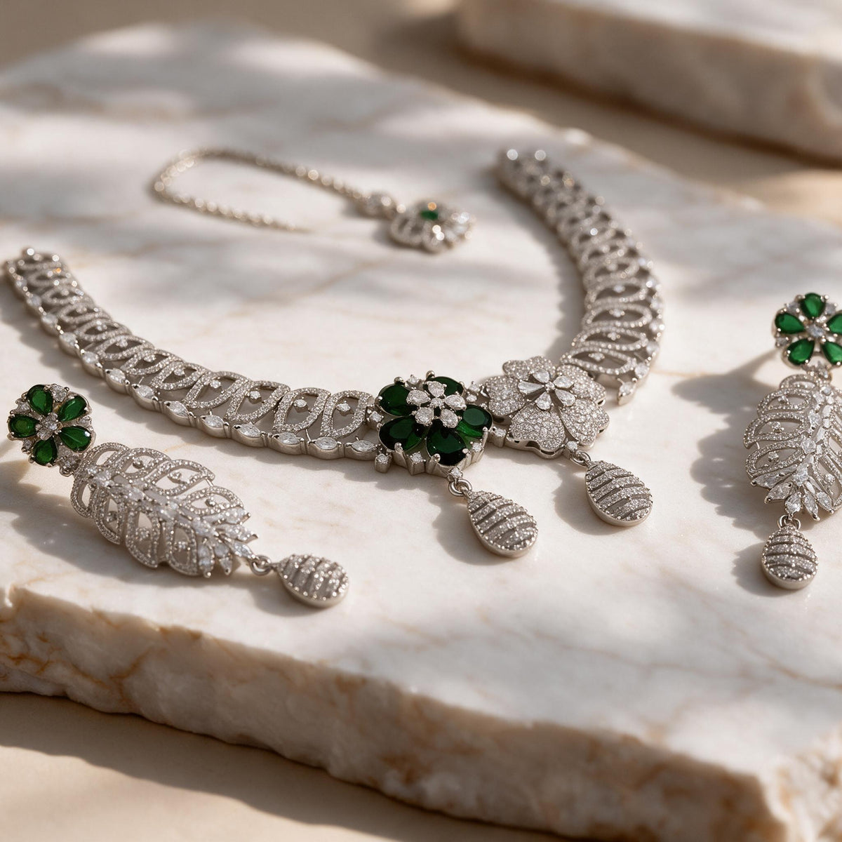 Close-up of the contrasting green and clear flower motifs and two teardrop pendants on the Meher necklace.