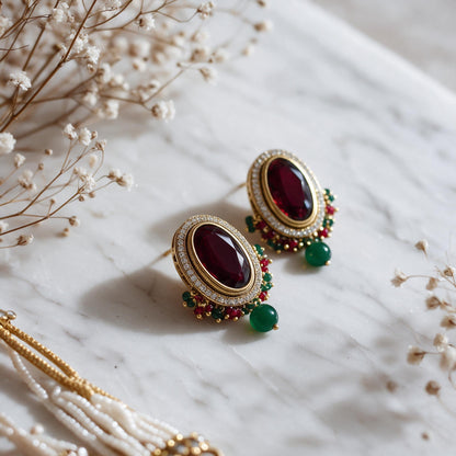 Matching burgundy oval earrings with clear surrounds and green bead drops.