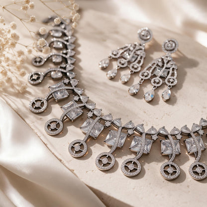 Angled close-up of square accents, circular necklace drops and matching earrings.